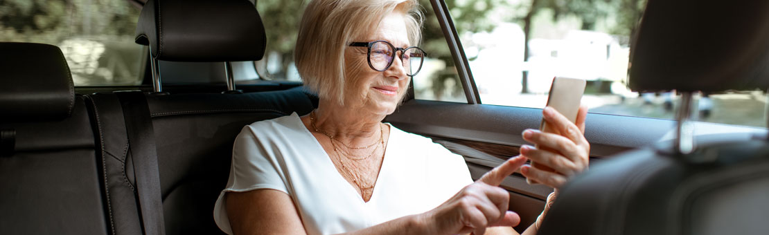 senior woman viewing her phone while sitting in car